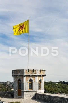 Close-up of castle turret with flag waving on pole with blue sky and clouds Stock Photos
