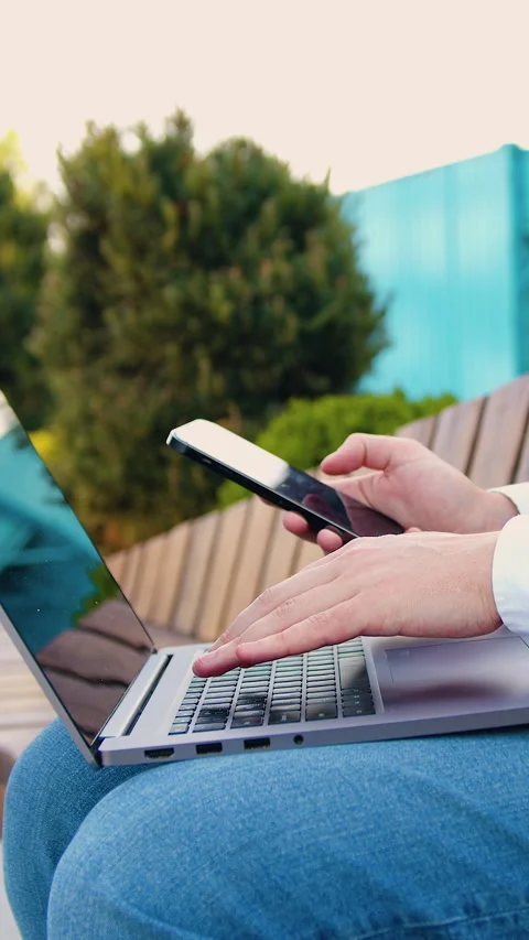 Close up of casual man or freelancer working on laptop computer and holding mobi Stock Footage 327547742