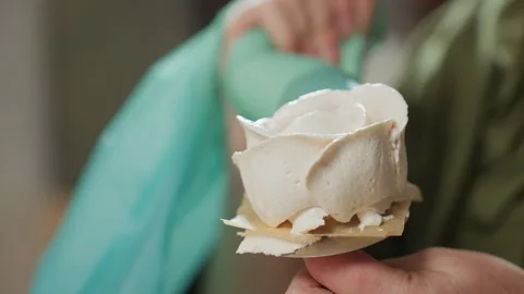 Close Up of Caterer Using Piping Bag to Coat Icing Flower on Baking Tool Stock Footage 307125811