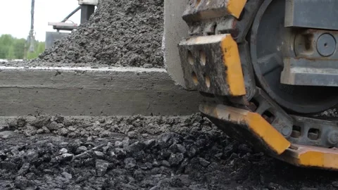 Close-up of caterpillar tread of crawler moving along edge of concrete roadbed Stock Footage 158049826