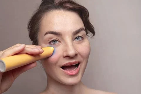 Close up of Caucasian attractive woman using microcurrent facial toning device 스톡 사진