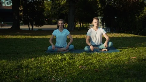 Close-up caucasian couple take a rest in the park practising yoga poses deep Stock Footage 117566341
