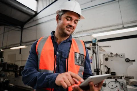 Close up of caucasian engineer scrolling on digital tablet researching Stock Photos