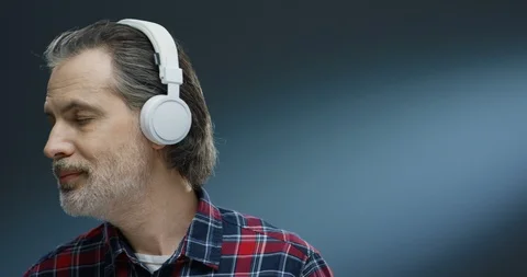 Close up of Caucasian gray-haired man in big headphones and motley shirt Stock Footage 125464429