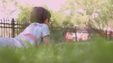 Close up Caucasian little boy using Digital Tablet sitting on the grass outdoors Stock Footage 211403534