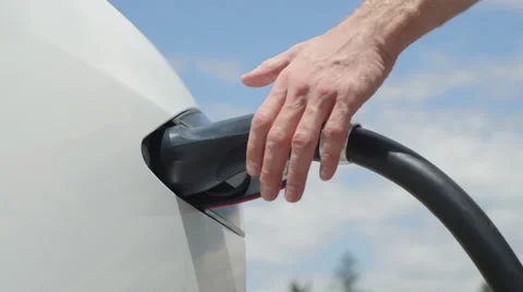CLOSE UP: Caucasian man unplugging Tesla car from electricity grid on sunny day Stock Footage