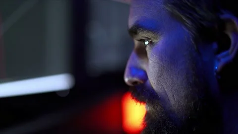 Close up of a Caucasian man working late in a dark room illuminated by the Stock Footage 234620612