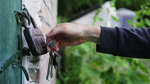 Close-up of a caucasian man's hand opens old padlock that is hanging Stock Footage 199687376