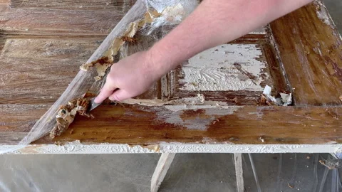 Close-up of a caucasian man's hands scraping white paint off a wooden door with  Stock Footage 274874274