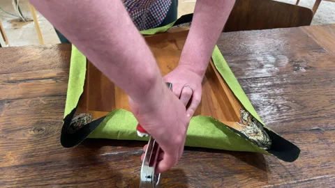Close up of caucasian man's hands using a staple gun to reupholster a dining roo Stock Footage 259906159