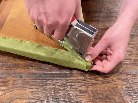 Close up of caucasian man's hands using a staple gun to reupholster a dining roo Stock Photos