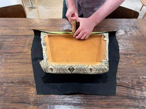 Close up of caucasian man's hands using a staple gun to reupholster a dining roo Stock Photos