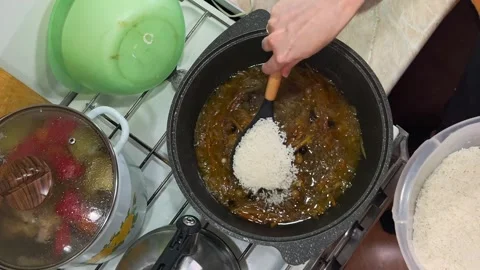 Close-up of cauldron with pilaf with meat and vegetables, chef adds rice Stock Footage 329745669