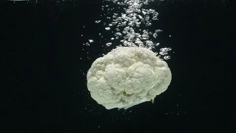 Close-up of cauliflower falling into the water against a black background. Stock Footage 273068504