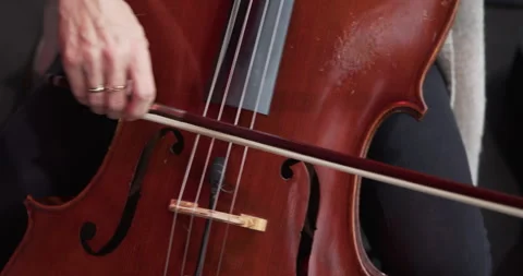 Close-up of cellist bowing strings near bridge during symphony performance. Stock Footage 313998911