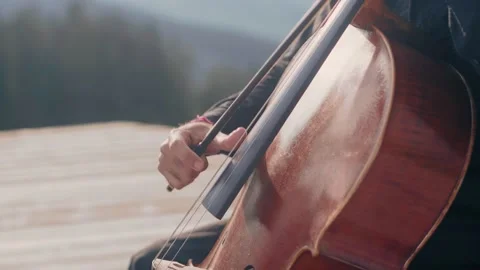 Close up of a cello player, playing pizzicato style outdoors in a warm Stock-Footage 142726145