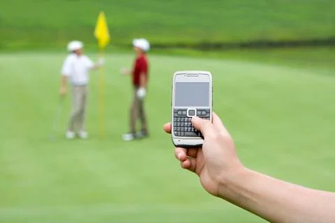 Close-up of a cellphone, two golfers in background Stock Photos