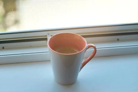 Close-up of a ceramic coffee mug filled with hot beverage placed on windowsil Stock Photos