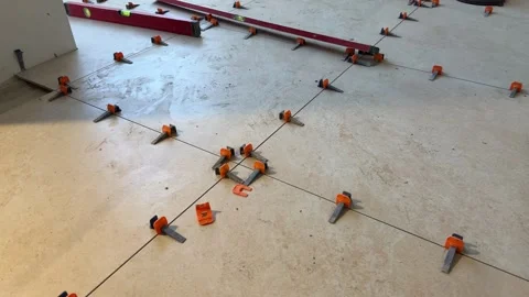 Close-up of ceramic floor tiles during installation with a tile leveling system Stock Footage 330538723