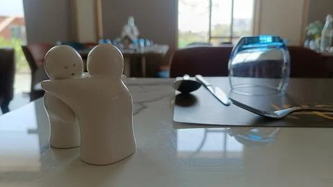 Close-up of ceramic hugging salt and pepper shakers on a restaurant table, with  Stock Photos