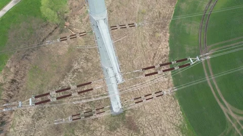 Close-up of ceramic insulators on high-voltage power line with city and ind.. Video stock 240927347