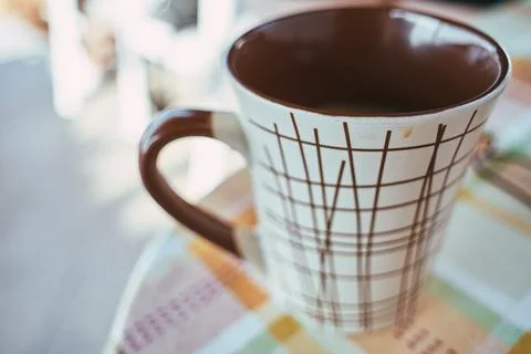 Close-up of a ceramic mug with brown and white geometric pattern on a table Stock Photos