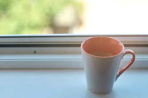 Close-up of a ceramic mug filled with fresh coffee sitting on a window sill Stock Photos