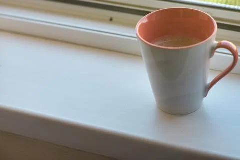 Close-up of a ceramic mug filled with fresh hot coffee on a white windowsill Stock Photos
