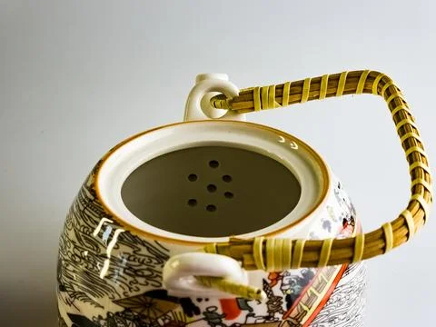 Close-up. Ceramic teapot with abstract pattern and wicker straw handle on a w Foto stock