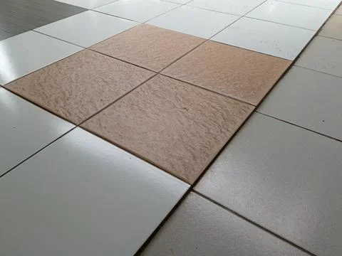 Close up of ceramic tile floor with square inset of textured beige tiles am.. Stock Photos