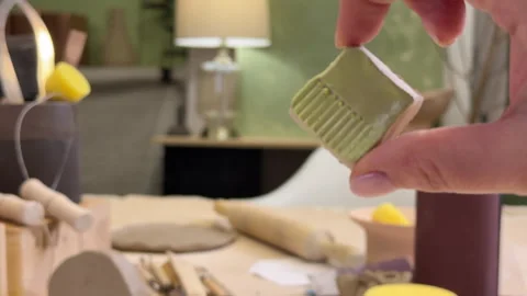Close-up of a ceramic tile sample in hand against the green wall of a pottery wo Stock Footage 306091659