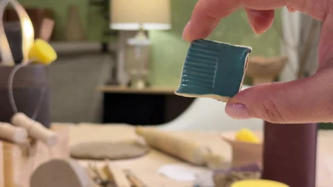 Close-up of a ceramic tile sample in hand against the green wall of a pottery wo Stock Footage 306092798