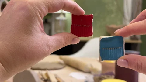 Close-up of a ceramic tile sample in hand against the green wall of a pottery wo Stock Footage 306093623
