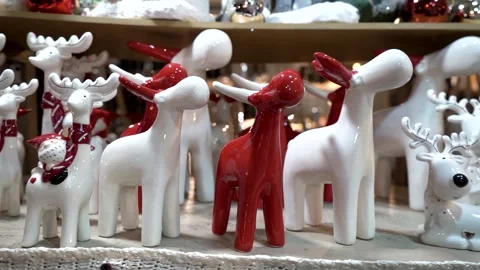 Close-up of ceramic white and red figurines of deer at a winter Christmas market Stock Footage 255240414
