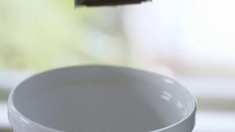 Close-up of cereal falling into white bowl Stock Footage 84456097