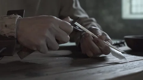 Close up of chained prisoner hands sharpening a goose quill inside a dungeon 스톡 동영상 340079571