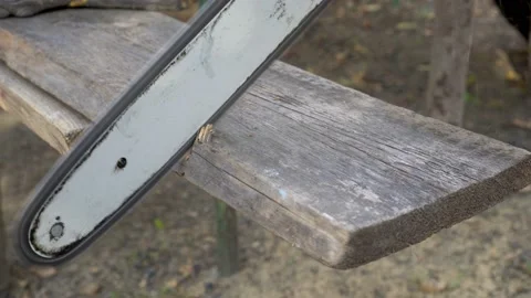 Close-up of a chainsaw blade that cuts off a piece from an old wooden Board.  Video stock 98593829
