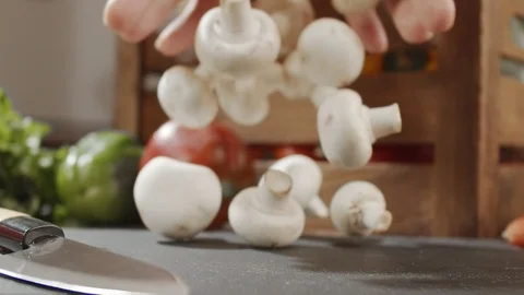 Close-up of champignon mushrooms falling on the kitchen table in slow motion Stock Footage 123963625
