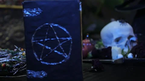 Close-up, change of focus from human skull to black book with pentagram. Vídeos de archivo 141836422