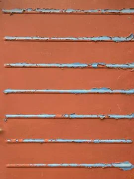 Close up of chapped red paint and metal lines going across abstract backgroun Foto stock