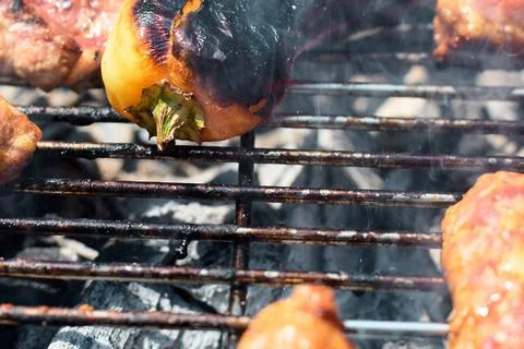 Close-up of charred bell pepper and meat grilling over open fire coals Stock Photos