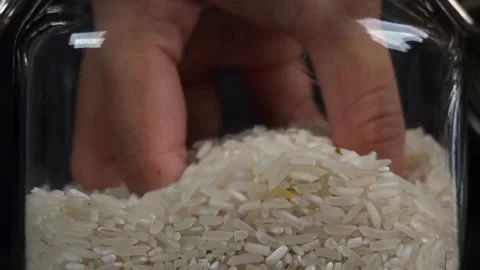 Close up of checking rice in glass jar by hand isolated black background 库存影片 278017914