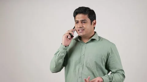 Close up of cheerful Asian man having phone call at workplace white background. Vídeo Stock 169907346