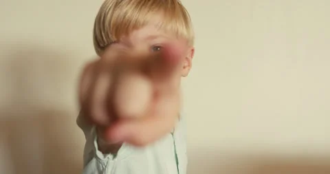 A close-up of a cheerful boy pointing his index finger at the camera and 스톡 동영상 324766874