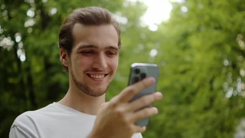Close up of a cheerful guy in a white t-shirt texting on his mobile phone o.. Stock-Footage 335206679