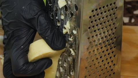 Close-Up of Cheese Being Grated with Kitchen Grater Stock Footage 311318402