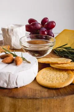 Close-up of cheese by grapes with almonds and crackers on wooden board, copy Stock Photos