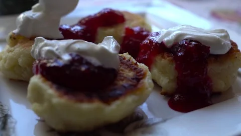 Close-up cheese pancakes with berry jam and sour cream. Slow Motion. HD Video stock 71645574