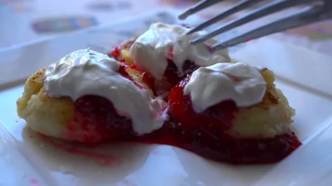 Close-up cheese pancakes with berry jam and sour cream. Eating with spoon. Slow Video stock 71763347