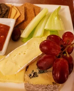 Close up of cheese platter with crackers celery and grapes Stock Photos